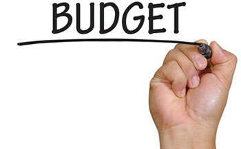 A hand writing the word budget on the web page