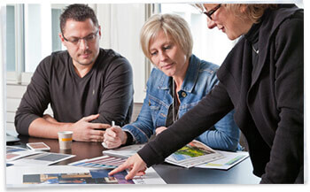 Man pointing at art board while co workers look on